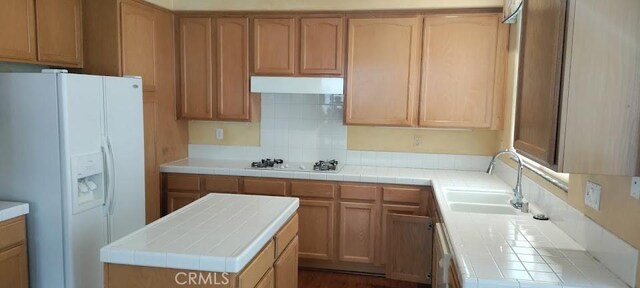 kitchen with sink, white appliances, tile counters, a kitchen island, and light brown cabinets