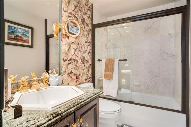 full bathroom featuring bath / shower combo with glass door, vanity, and toilet