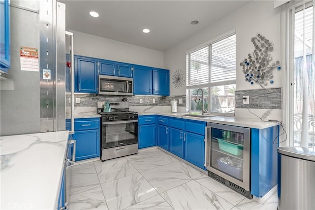 kitchen featuring blue cabinets, sink, wine cooler, and appliances with stainless steel finishes