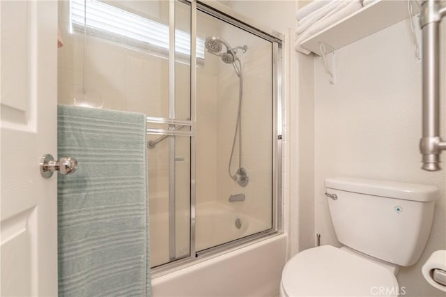 bathroom featuring bath / shower combo with glass door and toilet