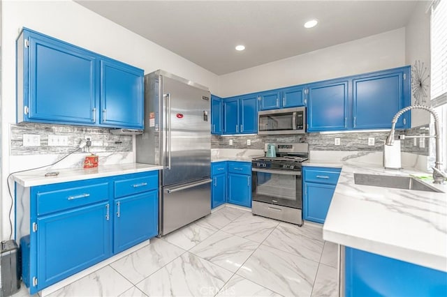 kitchen featuring sink, blue cabinetry, stainless steel appliances, light stone countertops, and decorative backsplash