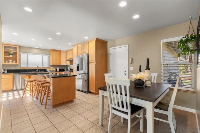 kitchen with appliances with stainless steel finishes, a center island, a wealth of natural light, and light tile patterned floors