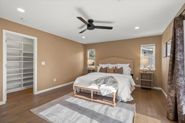 bedroom featuring ceiling fan, a walk in closet, dark hardwood / wood-style flooring, and a closet