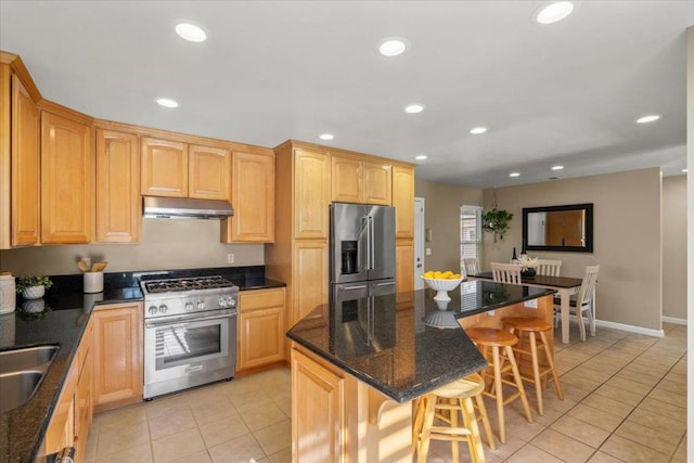 kitchen with light tile patterned floors, a breakfast bar, premium appliances, a kitchen island, and dark stone counters