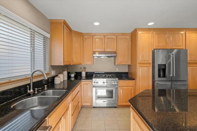 kitchen with light tile patterned floors, dark stone countertops, sink, and premium appliances