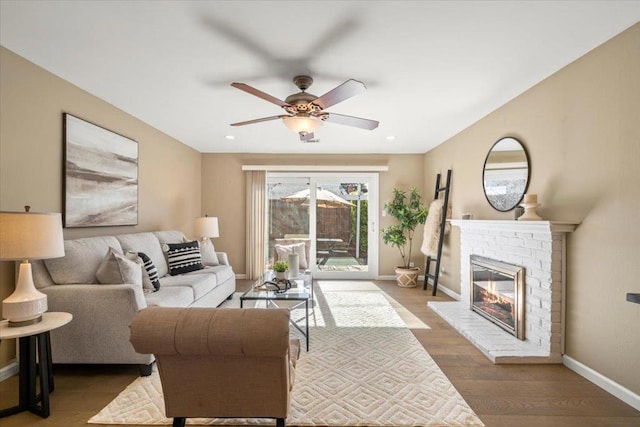 living room with hardwood / wood-style flooring, ceiling fan, and a fireplace