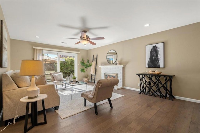 living room with dark hardwood / wood-style flooring, a fireplace, and ceiling fan