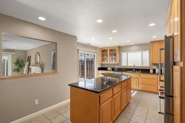 kitchen featuring light tile patterned flooring, high end fridge, sink, and a kitchen island