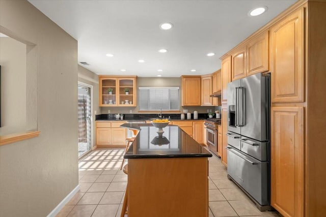 kitchen featuring light brown cabinets, a center island, light tile patterned floors, and premium appliances