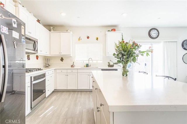 kitchen with white cabinetry, stainless steel appliances, sink, and a kitchen island