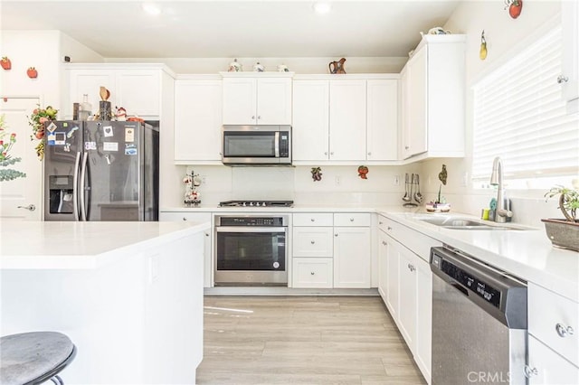 kitchen with white cabinetry, sink, stainless steel appliances, and light hardwood / wood-style floors