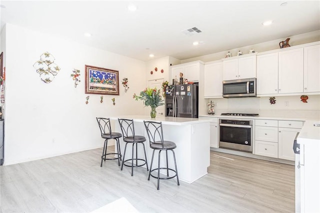 kitchen with stainless steel appliances, a center island, a breakfast bar area, and white cabinets