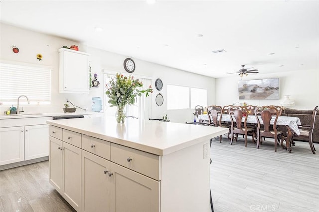 kitchen featuring sink, ceiling fan, white cabinetry, a center island, and light hardwood / wood-style floors