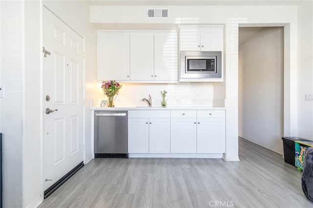 kitchen featuring white cabinetry, sink, stainless steel appliances, and light hardwood / wood-style floors