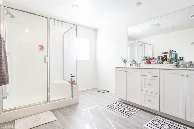 bathroom with an enclosed shower, vanity, and wood-type flooring