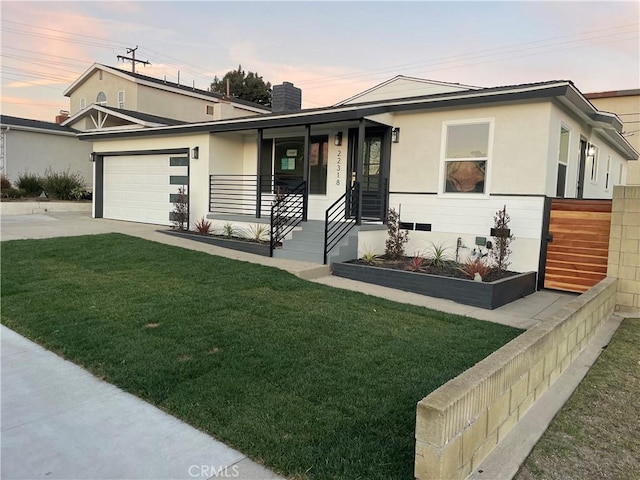 view of front of house with a garage, a lawn, and covered porch