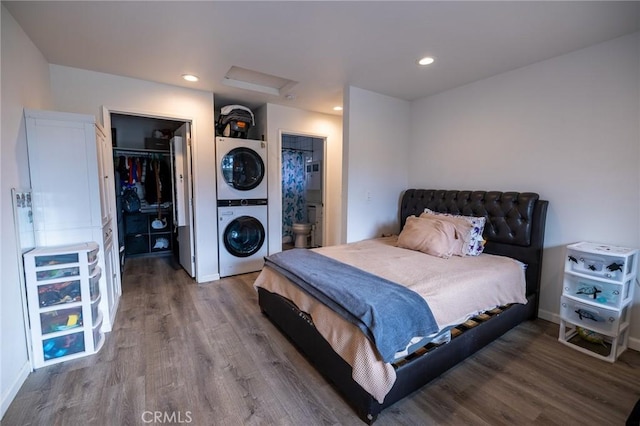 bedroom featuring stacked washer / drying machine, ensuite bath, a spacious closet, a closet, and hardwood / wood-style flooring