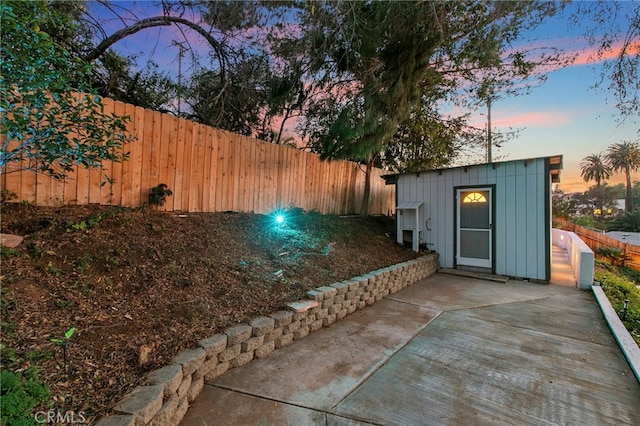 yard at dusk featuring a patio and an outbuilding