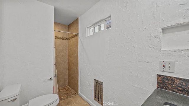 bathroom featuring tile patterned floors, toilet, and tiled shower