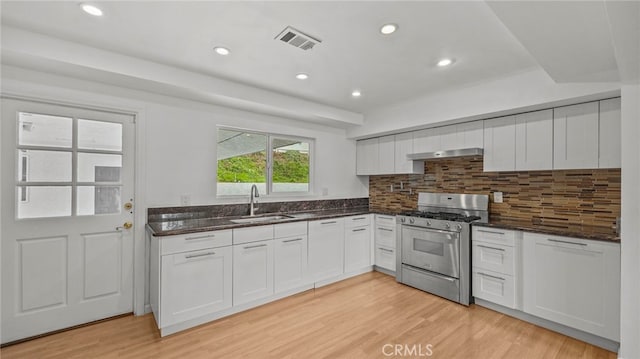 kitchen with sink, white cabinets, decorative backsplash, gas range, and light hardwood / wood-style flooring