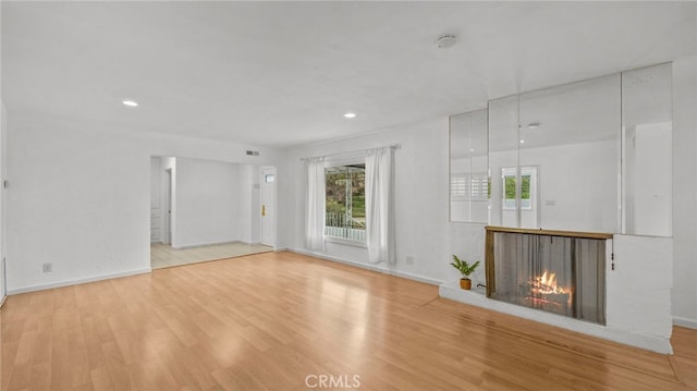 unfurnished living room with light hardwood / wood-style flooring and a multi sided fireplace