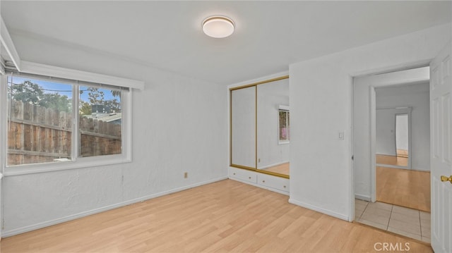 unfurnished bedroom with light hardwood / wood-style floors and a closet