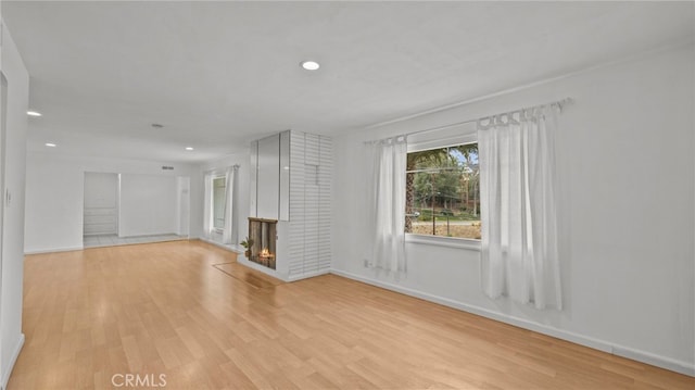 unfurnished living room featuring a brick fireplace and light hardwood / wood-style flooring