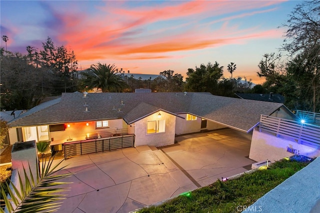 back house at dusk featuring a patio