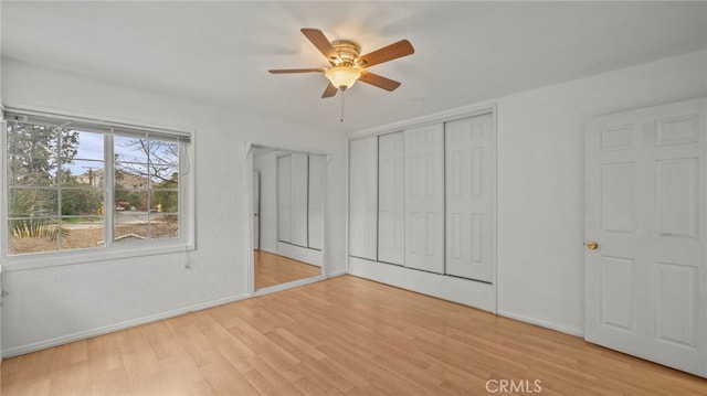 unfurnished bedroom with ceiling fan, a closet, and light wood-type flooring