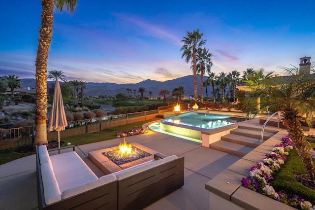 pool at dusk featuring a patio, a mountain view, and an outdoor fire pit