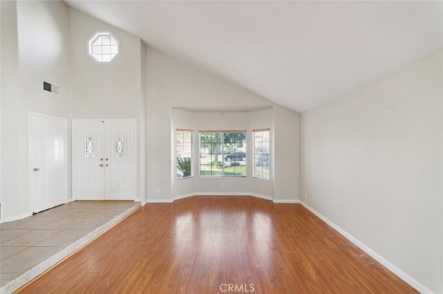 unfurnished living room with high vaulted ceiling, light hardwood / wood-style floors, and a healthy amount of sunlight