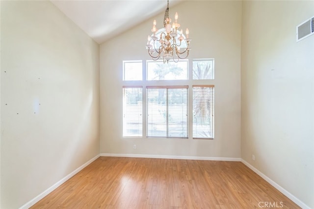 unfurnished room with high vaulted ceiling, a notable chandelier, and light wood-type flooring