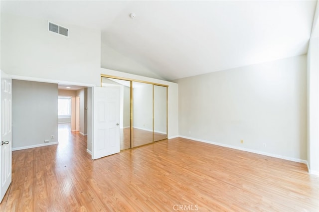 unfurnished bedroom with high vaulted ceiling, light hardwood / wood-style floors, and a closet