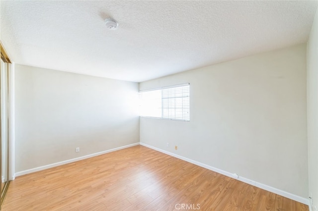 spare room featuring light hardwood / wood-style floors and a textured ceiling