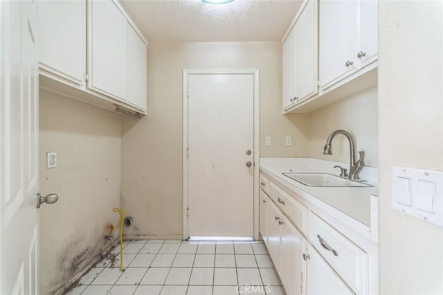 laundry area with sink, light tile patterned floors, and a textured ceiling