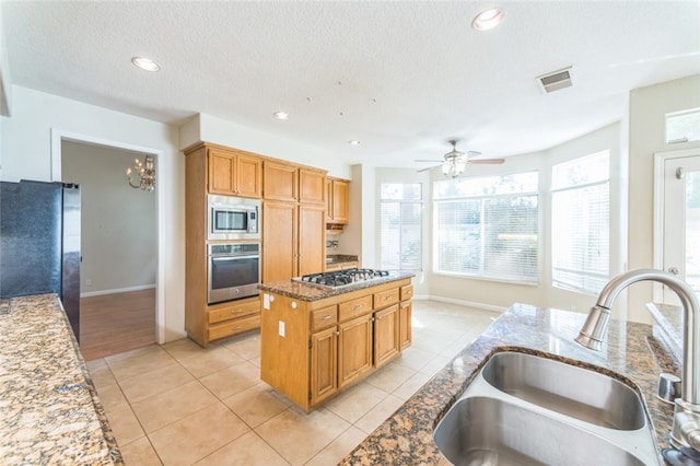 kitchen with sink, light tile patterned floors, stainless steel appliances, and a center island