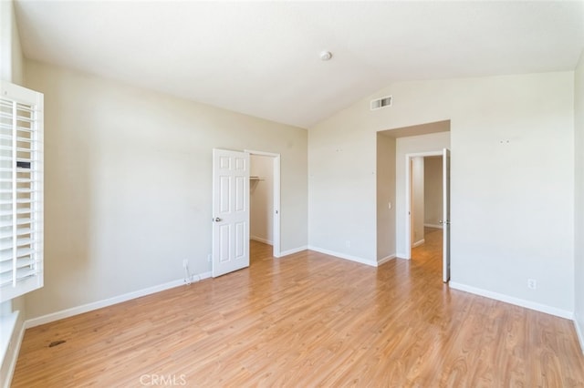 spare room with lofted ceiling and light wood-type flooring