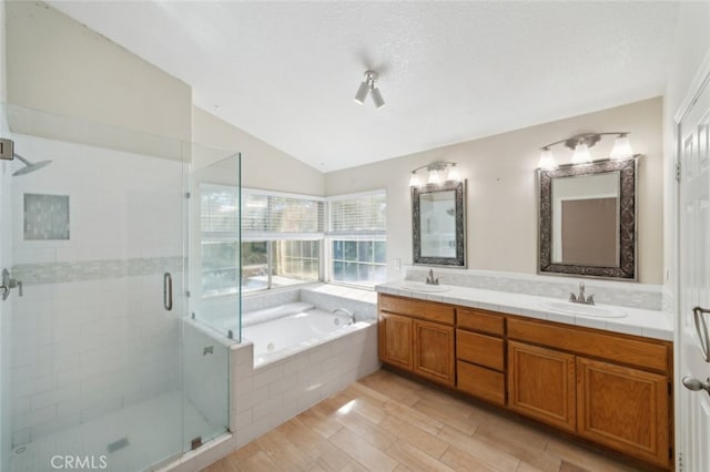 bathroom featuring vaulted ceiling, shower with separate bathtub, hardwood / wood-style floors, vanity, and a textured ceiling