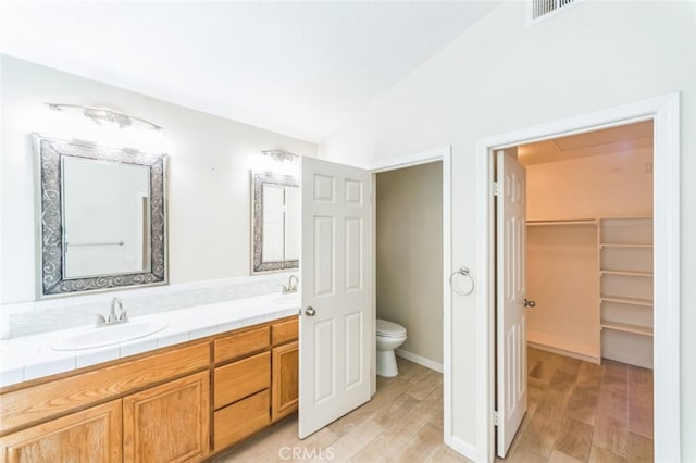 bathroom featuring vanity, toilet, vaulted ceiling, and hardwood / wood-style floors