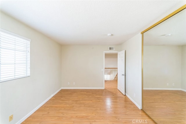 empty room with light hardwood / wood-style floors and a textured ceiling