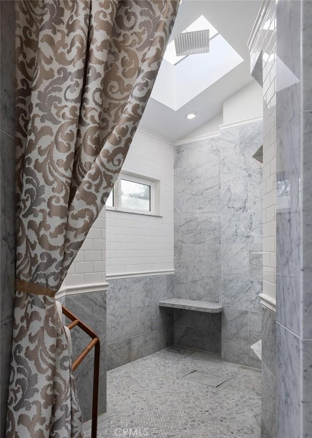 bathroom with crown molding, a skylight, and tiled shower