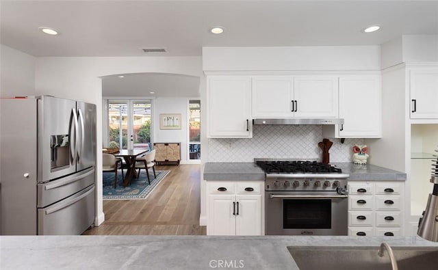 kitchen with sink, white cabinetry, backsplash, stainless steel appliances, and light wood-type flooring