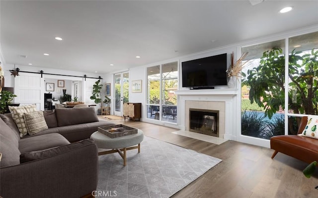 living room featuring wood-type flooring, a barn door, floor to ceiling windows, and a tile fireplace