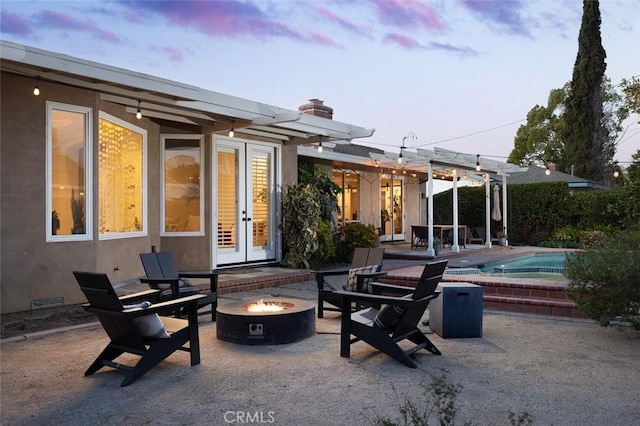 back house at dusk featuring a patio, a pergola, and a fire pit