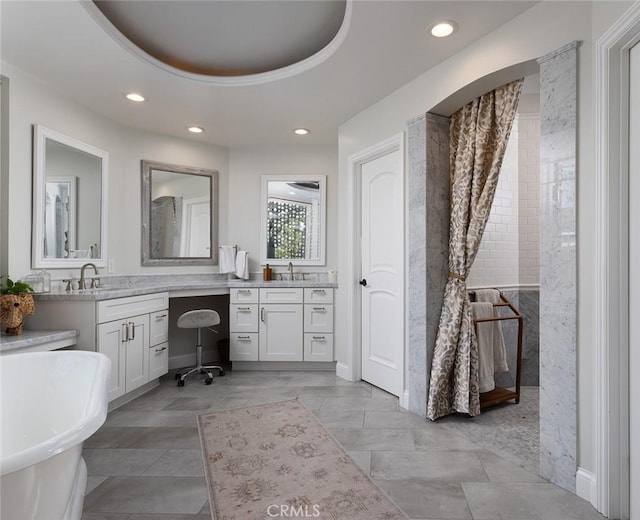 bathroom with vanity, a tub to relax in, and a tray ceiling