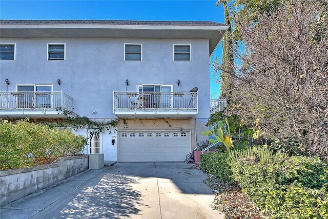 rear view of property with a garage and a balcony