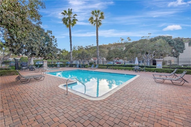 community pool with a patio area and fence