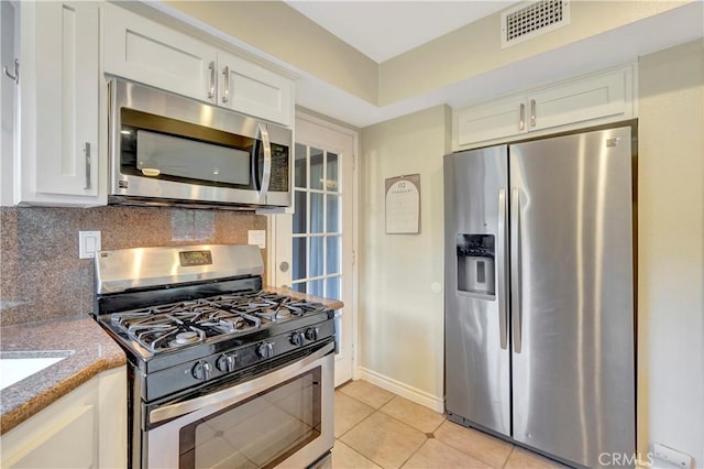 kitchen with light tile patterned floors, visible vents, decorative backsplash, white cabinets, and appliances with stainless steel finishes