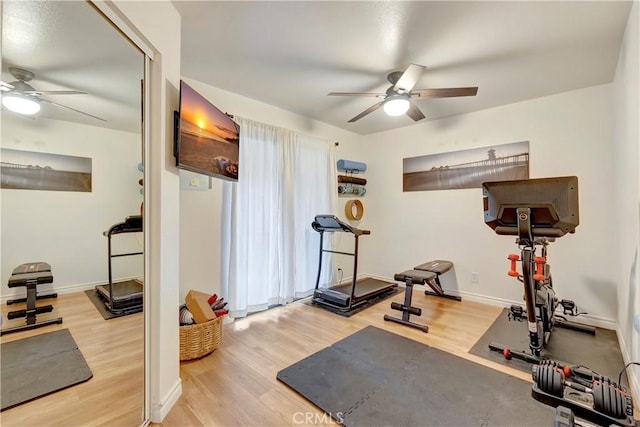 workout room with baseboards, a ceiling fan, and wood finished floors