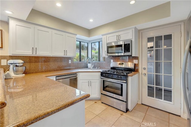 kitchen with tasteful backsplash, white cabinets, stainless steel appliances, and a sink